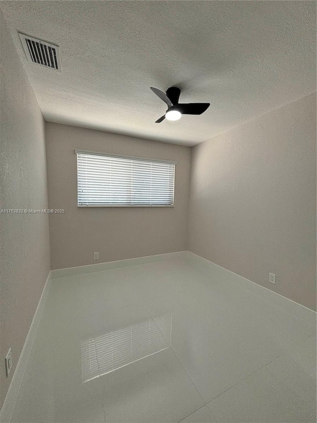 unfurnished room with visible vents, a textured ceiling, and a ceiling fan