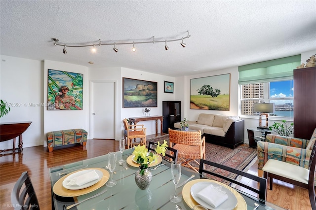 dining area with a textured ceiling, baseboards, and wood finished floors