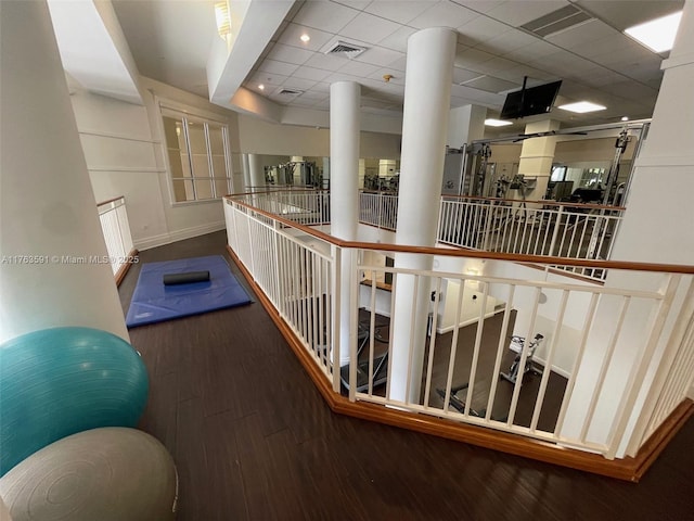 interior space with visible vents, a paneled ceiling, baseboards, and wood finished floors