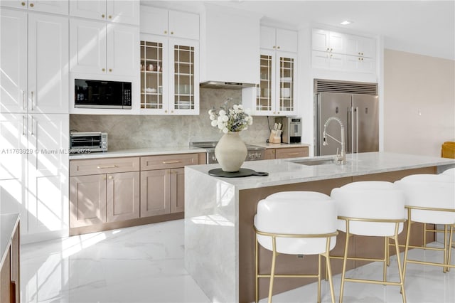 kitchen with tasteful backsplash, marble finish floor, built in appliances, and a sink