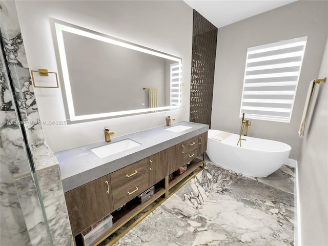 bathroom featuring a sink, a freestanding bath, marble finish floor, and double vanity