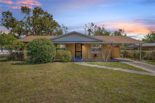 single story home featuring driveway, an attached carport, central AC, and a front yard