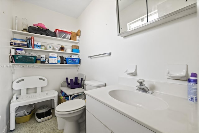 bathroom with speckled floor, toilet, and vanity