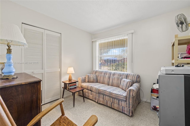 living area featuring baseboards, speckled floor, and a textured ceiling