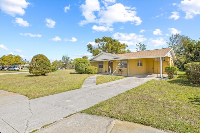 ranch-style home featuring stucco siding, a front yard, an attached carport, and driveway