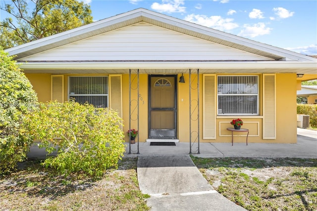 bungalow-style home featuring central AC unit, covered porch, and stucco siding