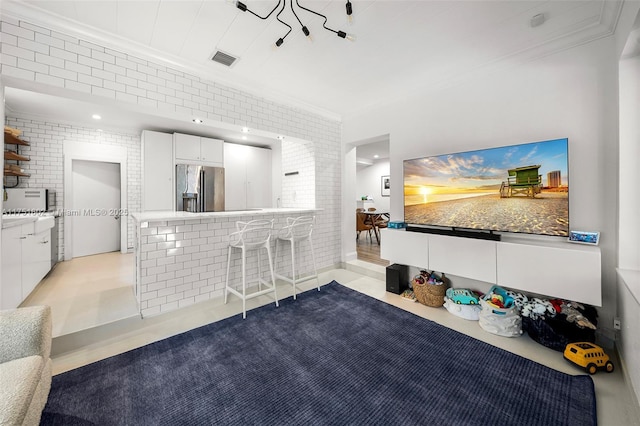 living area with visible vents, brick wall, crown molding, and tile patterned flooring