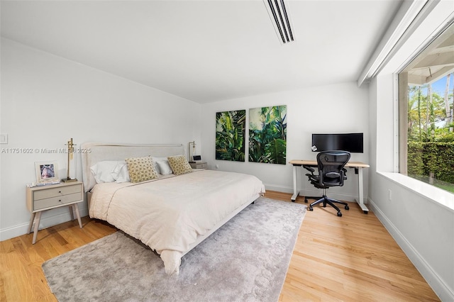 bedroom with visible vents, baseboards, and wood finished floors