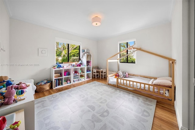 game room featuring a healthy amount of sunlight, wood finished floors, and crown molding