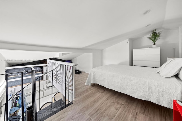 bedroom featuring baseboards, lofted ceiling, and wood finished floors