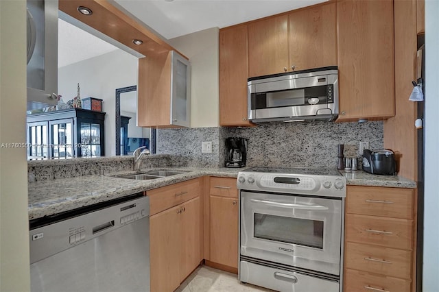 kitchen with decorative backsplash, appliances with stainless steel finishes, light stone countertops, and a sink