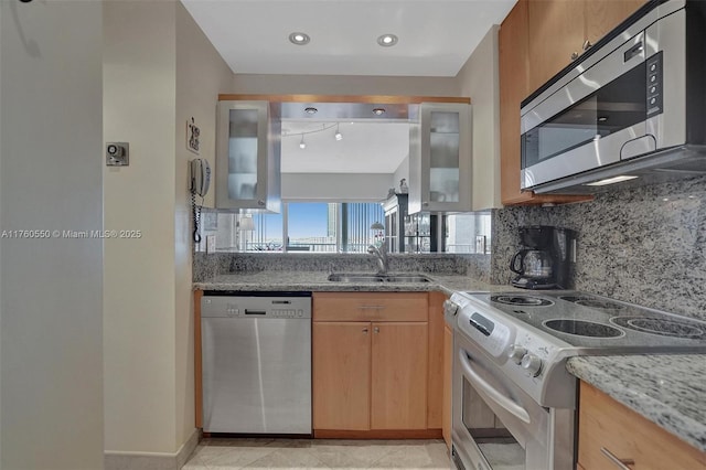 kitchen with tasteful backsplash, light stone counters, recessed lighting, appliances with stainless steel finishes, and a sink