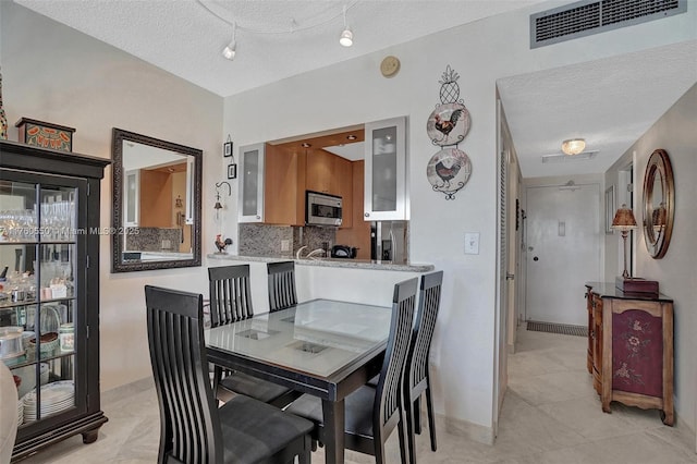 dining room with visible vents, a textured ceiling, and baseboards