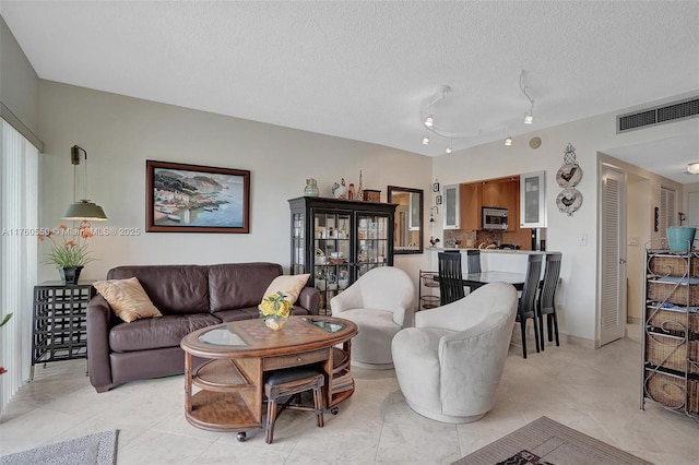 living room with light tile patterned floors, visible vents, and a textured ceiling