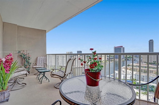 balcony with outdoor dining space, a view of city, and a water view