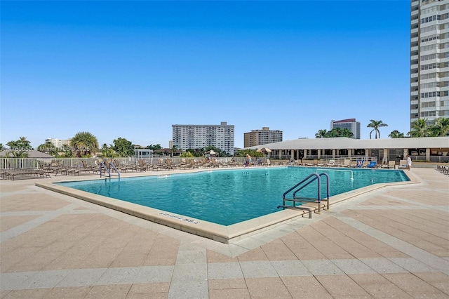 pool featuring a patio area, a city view, and fence