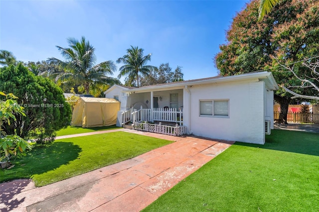 view of front of house featuring stucco siding, a front yard, and fence