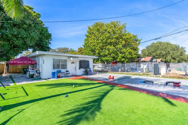 back of house featuring stucco siding, an outbuilding, a patio, fence, and a yard