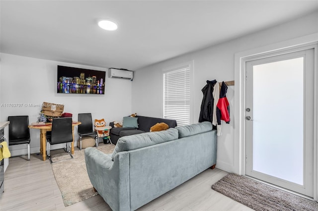 living room featuring an AC wall unit, baseboards, and light wood finished floors