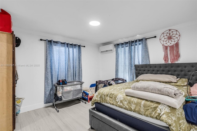 bedroom with crown molding, wood finished floors, baseboards, and a wall mounted air conditioner