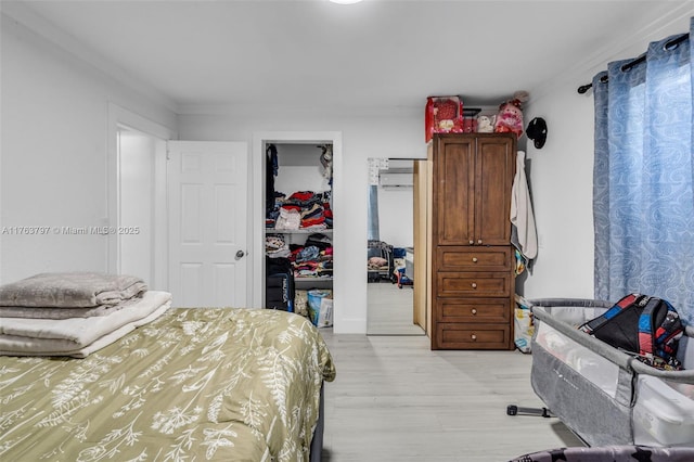 bedroom with a spacious closet, light wood-style flooring, and a closet