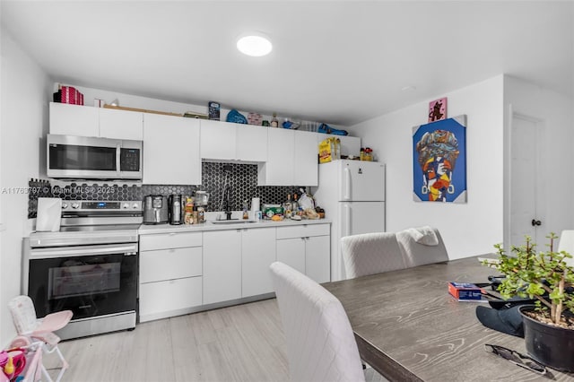 kitchen featuring a sink, decorative backsplash, white cabinets, and stainless steel appliances