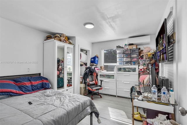 bedroom with light wood-style flooring and a wall mounted AC