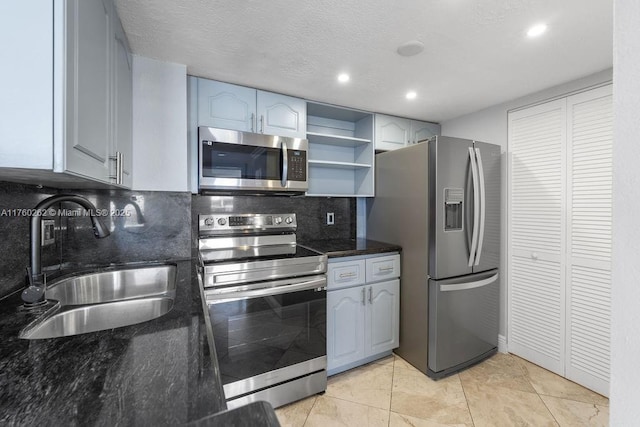 kitchen featuring a sink, backsplash, dark stone countertops, appliances with stainless steel finishes, and open shelves