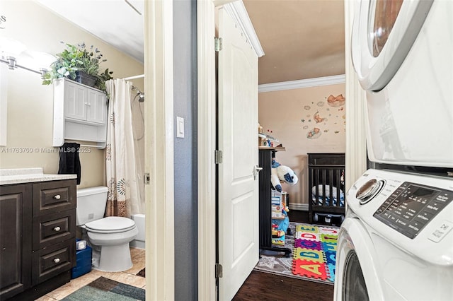 clothes washing area with stacked washer / drying machine, laundry area, and crown molding