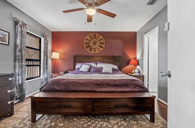 bedroom featuring visible vents, baseboards, ceiling fan, wood finished floors, and a textured ceiling