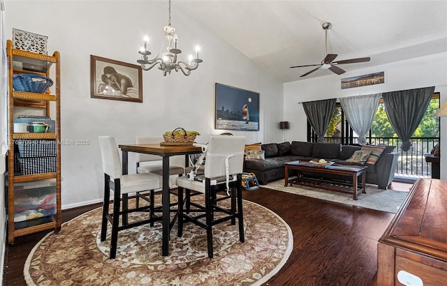 dining area with dark wood-type flooring, ceiling fan with notable chandelier, baseboards, and vaulted ceiling