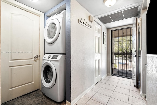 laundry area featuring tile patterned floors, visible vents, stacked washer and dryer, baseboards, and laundry area