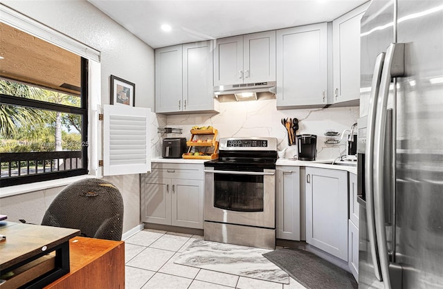 kitchen featuring under cabinet range hood, gray cabinets, stainless steel appliances, and backsplash