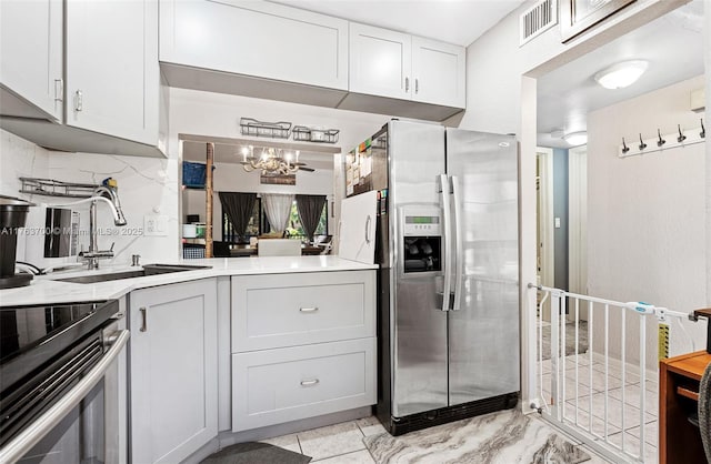 kitchen featuring visible vents, a chandelier, light countertops, stainless steel fridge, and a sink