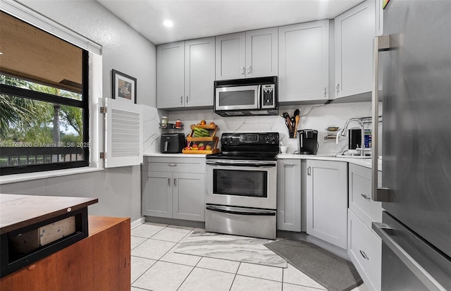 3059 Carambola Cir S Unit 2033, Coconut Creek, FL 33066 - kitchen featuring stainless steel appliances, gray cabinets, light countertops, light tile patterned floors, and tasteful backsplash