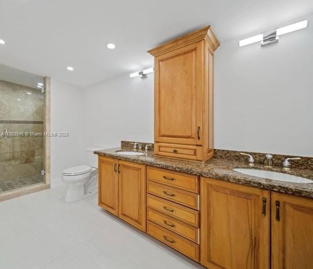 bathroom featuring toilet, double vanity, recessed lighting, a stall shower, and a sink