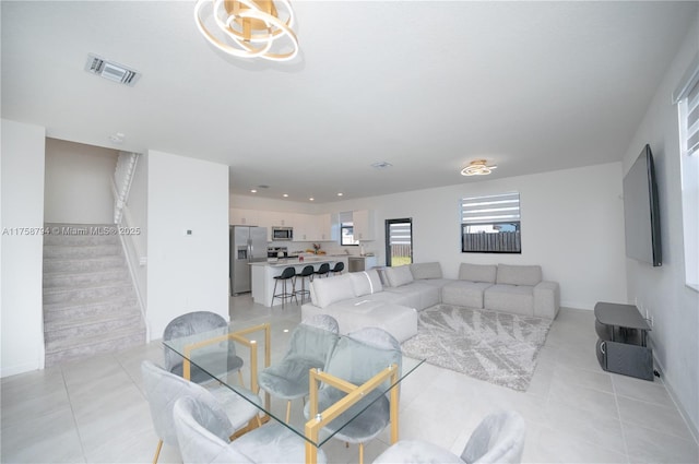 living area with light tile patterned floors, stairway, baseboards, and visible vents