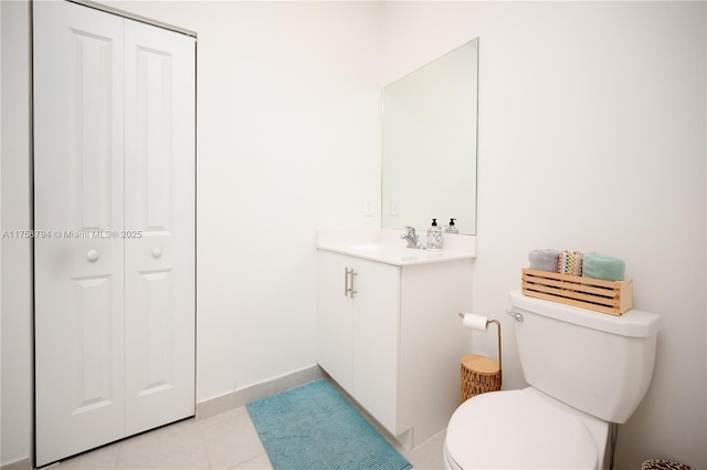 half bath featuring vanity, tile patterned floors, toilet, and a closet