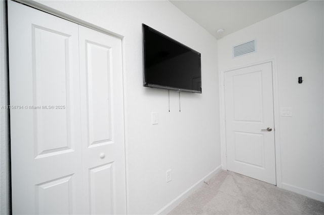 unfurnished bedroom featuring light carpet, visible vents, a closet, and baseboards