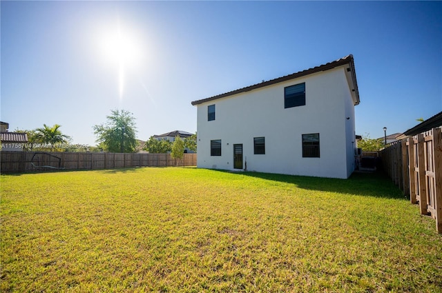 back of property featuring stucco siding, a lawn, and a fenced backyard