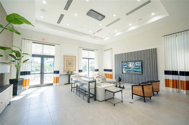 living area with visible vents, french doors, a high ceiling, and a tray ceiling