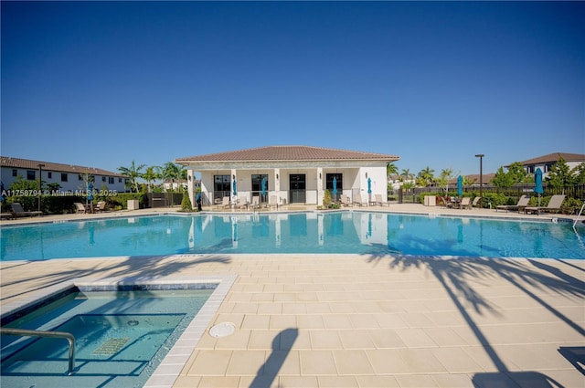 pool featuring a patio area, a community hot tub, and fence