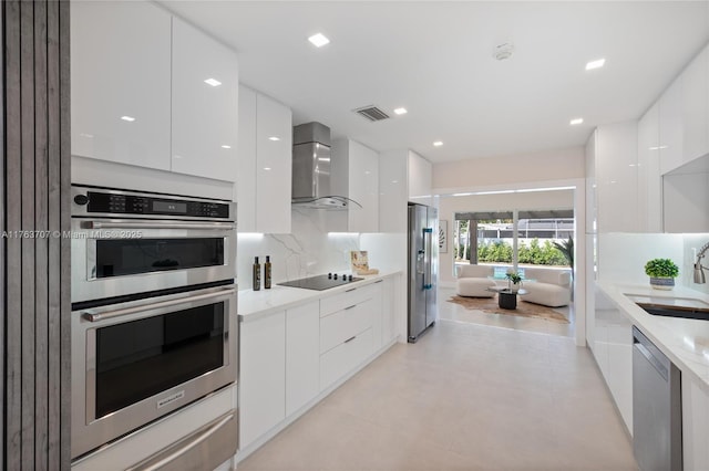 kitchen featuring a sink, appliances with stainless steel finishes, white cabinetry, wall chimney exhaust hood, and modern cabinets