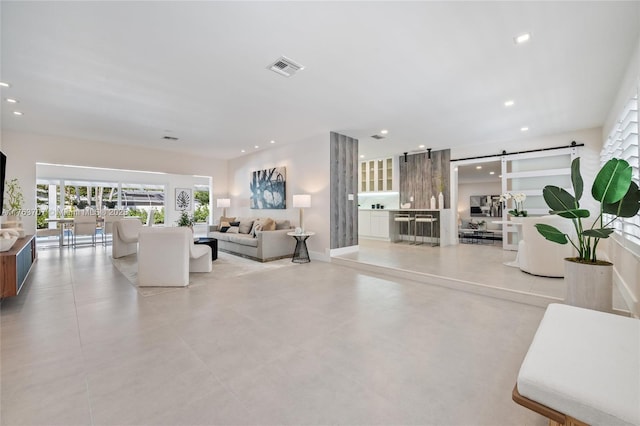 living room with visible vents, recessed lighting, baseboards, and a barn door