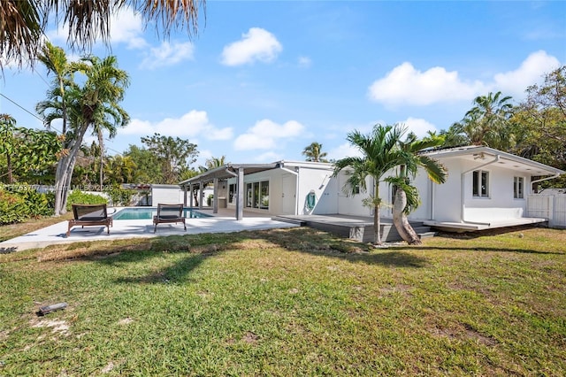 rear view of property with stucco siding, a lawn, a patio, fence, and an outdoor pool