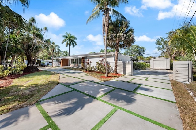 view of front of home featuring an outbuilding, fence, driveway, stucco siding, and a detached garage