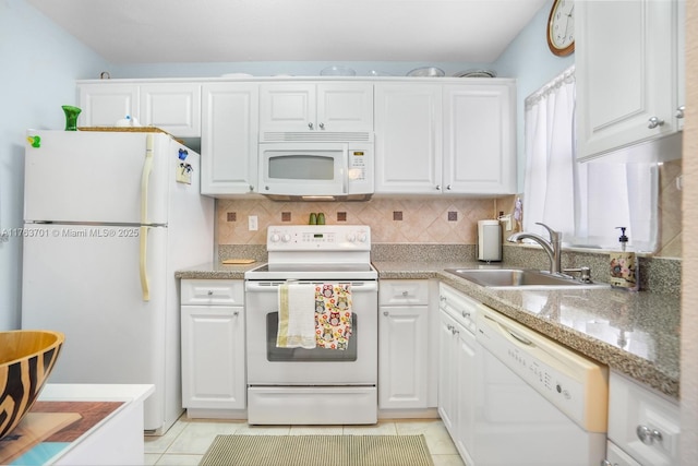 kitchen featuring white appliances, light tile patterned floors, a sink, white cabinets, and backsplash