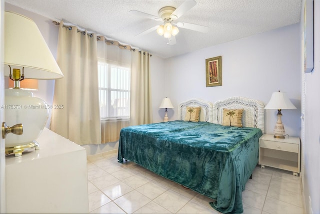 bedroom with ceiling fan, light tile patterned floors, and a textured ceiling