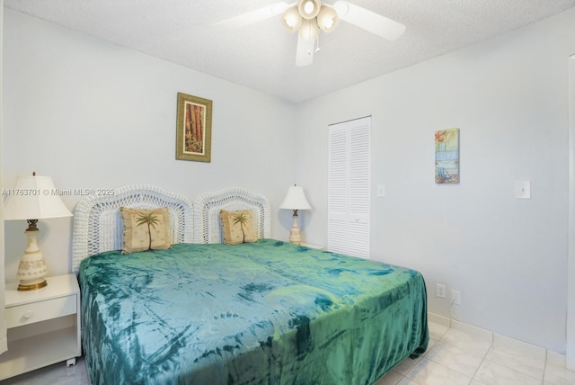 bedroom featuring light tile patterned floors, a closet, a textured ceiling, and a ceiling fan