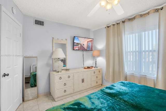 bedroom with ceiling fan, light tile patterned flooring, visible vents, and a textured ceiling